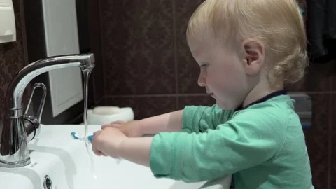 A small child, a boy, brushes his teeth on his own, early in the morning in the Stock Footage 130726844