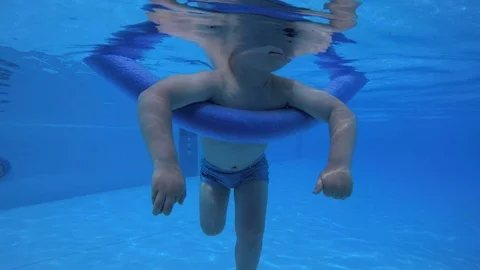 A small child, a boy floats on a stick for bathing, taking pictures underwater  Stock Footage 111414045