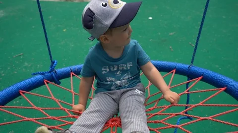 A small child, a boy in gray pants swing on a background of green cover Stock Footage 108737080