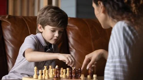 Small child boy learning playing chess with caring young mother. Stock Photos