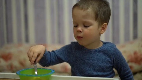 A small child (a boy) sits at a table and eats 스톡 동영상 127768293