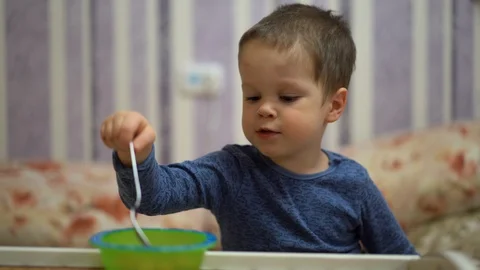 A small child (a boy) sits at a table and eats Stock Footage 128967960