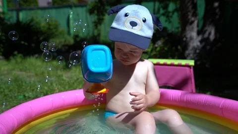 A small child boy sitting in an inflatable pool of water Stock Footage 111414196