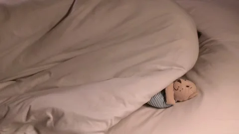 Small child boy sleeps restlessly hugging a teddy bear toy at night on bed. The Stock Footage 263864340