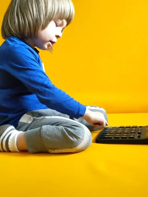 A small child counts on a calculator on a yellow background. Kid fingers press Stock Footage 270747765