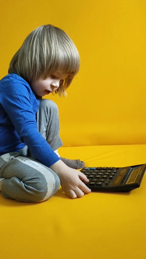 A small child counts on a calculator on a yellow background. Kid fingers press Stock Footage 274519294