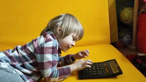 A small child counts on a calculator on a yellow background. Kid fingers press Stock Footage 274519322