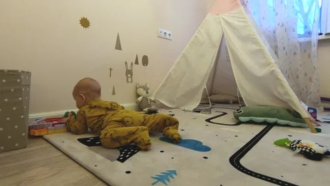 A small child crawls around the children's room at home alone Stock Footage 145460864