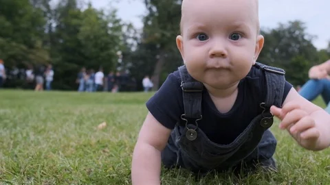 A small child crawls on the grass. Slow motion. 스톡 동영상 120732175