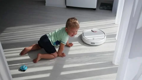 A small child crawls up to a robot dust and turns on. Stock Footage 131647151