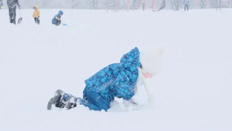 Small child crawls through the snow. Child walks outside and has fun Video stock 211675976