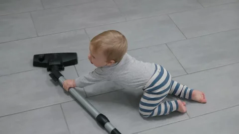 A small child crawls with a vacuum cleaner Stock Footage 318419031