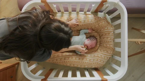Small child is crying in crib, mother calms her daughter with a pacifier Stock Footage 194829336
