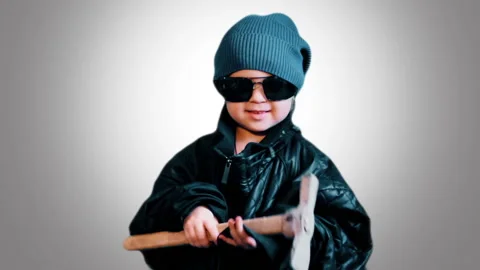 A small Child dressed as a Bully with a Hammer threatens people. Stock Footage 88490055