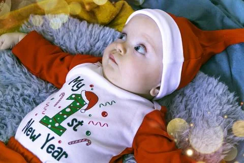 Small child is dressed in a Christmas costume and lies near the Christmas tree Stock Photos