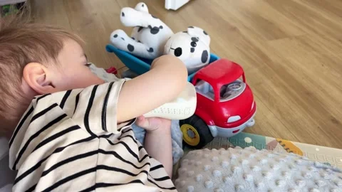 A small child drinks milk from a bottle, the baby is waving his legs Stock Footage 306253701