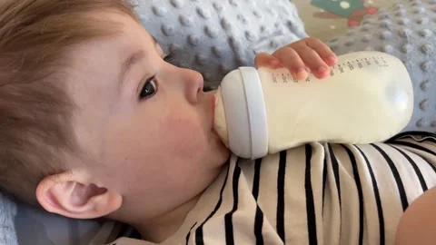A small child drinks milk from a bottle Stock Footage 306253728