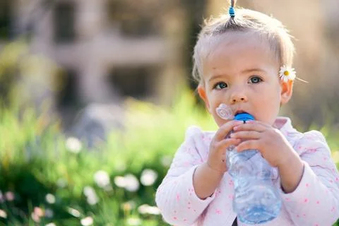Small child drinks from a plastic bottle. Close-up Stock Photos