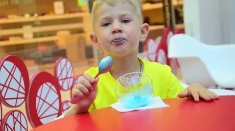 Small child eats blue icecream and puts out the tongue Stock Footage 64149240
