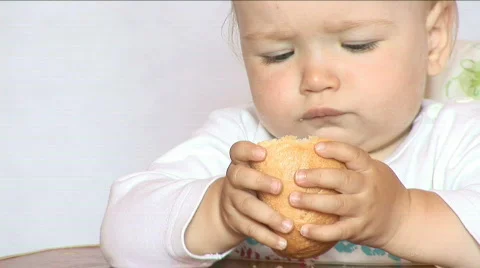  Small child eats bread behind a table Stock Footage 478255