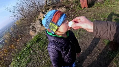 A small child eats a chicken egg. Walk in the mountains Video stock 223721493