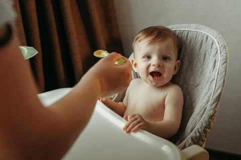 A small child eats vegetable puree. Mom feeds the baby Stock Photos