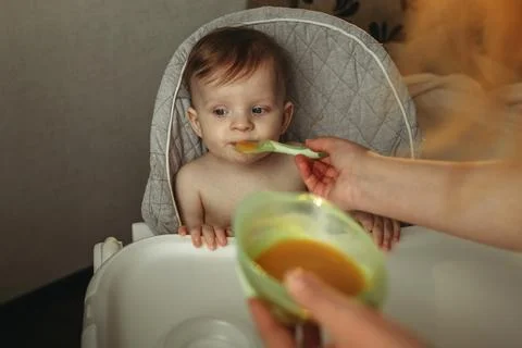 A small child eats vegetable puree. Mom feeds the baby Stock Photos