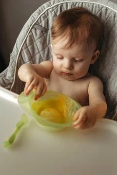 A small child eats vegetable puree without a spoon Stock Photos