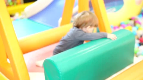 Small child exploring soft indoor obstacle elements while climbing and moving Stock Footage 321232352