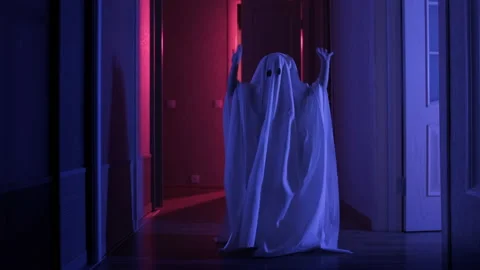Small child in ghost costume is having fun and dancing indoors in rays of Stock Footage 160438527