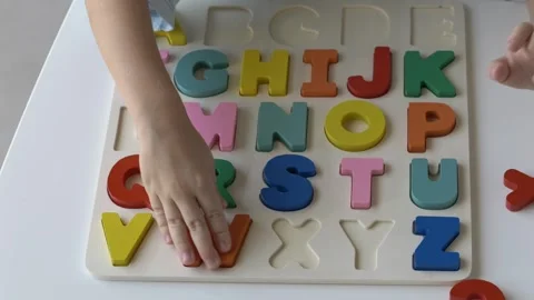 Small child hand is placing vibrant letters into colorful alphabet puzzle Video stock 318294531