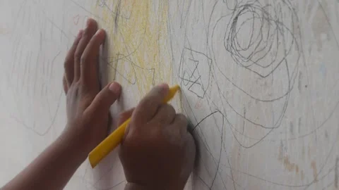 A small child hand is scribbling on a white wall with a crayon. 스톡 동영상 327731277