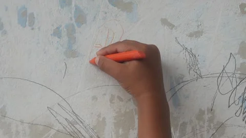 A small child hand is scribbling on a white wall with a crayon. Stock Footage 327731278