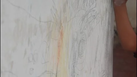 A small child hand is scribbling on a white wall with a crayon. 스톡 동영상 327731314