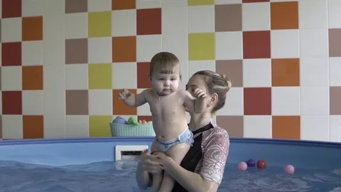 A small child is in the hands of the coach in the pool Stockbeeldmateriaal 85267662