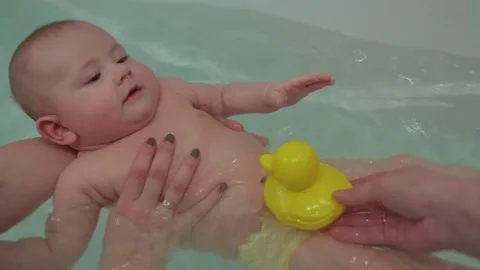 A small child has fun bathing in the bathroom with his toy - a yellow duck. Video stock 144338078