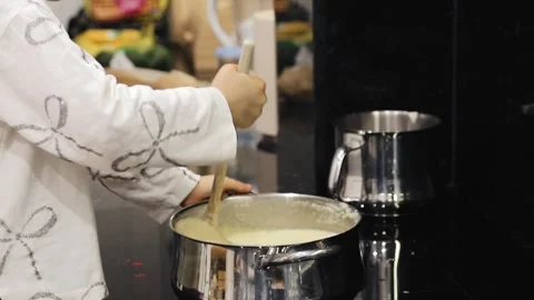 Small child helping in the kitchen stirring a creamy mashed potato mixture Stock Footage 321682364