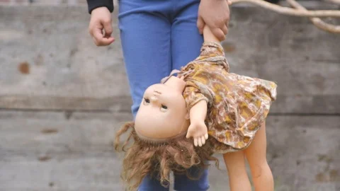 Small child holds an old broken doll by the hand and by the hair Stock Footage 100270218
