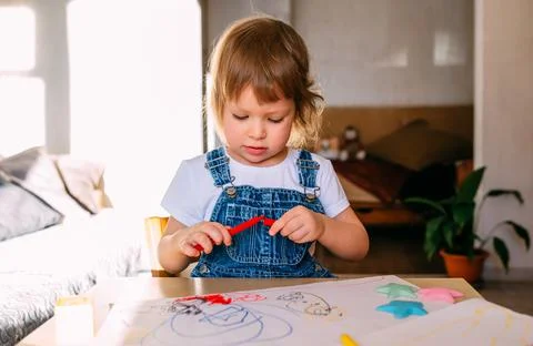 Small child at home at the children's table draws with felt-tip pens. Stock Photos