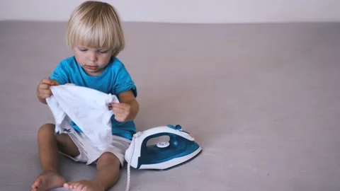 A small child irons his clothes on the bed Stock Footage 220731792