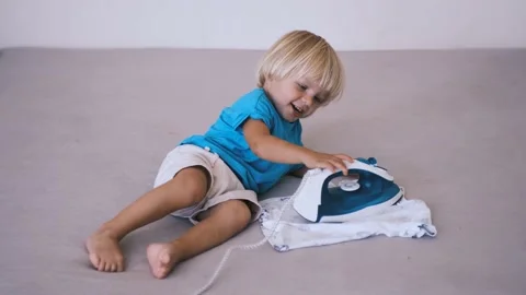 A small child irons his clothes on the bed Stock Footage 220732089
