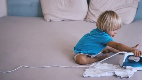 A small child irons his clothes on the bed Stock-Footage 220732106