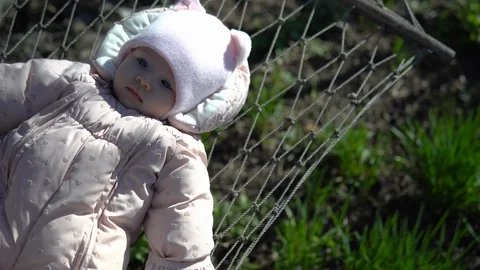 A small child in a jacket is swinging on a hammock. Stock Footage 129754736
