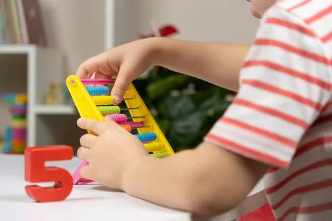 A small child learns to count on abacus, mathematics, arithmetic for children. Stock Photos