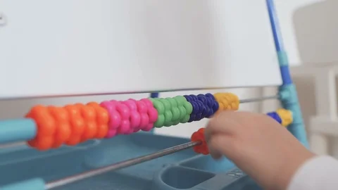 A small child learns to count by shifting divisions in toy bills. Stock Footage 102162484