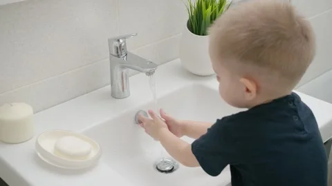 A small child learns to open a tap with water and wash his hands Stock Footage 130418456