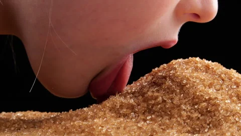 A small child licks and eats pure cane sugar with a pile of brown sugar. Tongue  Stock Footage 254133673