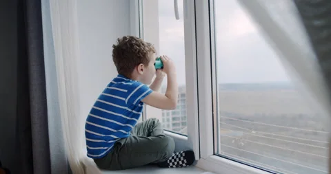 A small child, looking through binoculars outside the house window. Stock Footage 152680733