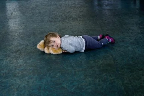 A small child lying on the cold floor with his toy under his head, lost children Stock-Fotos