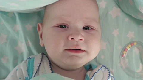 A small child is lying in a crib and looking at the camera.Close-up of the head. Stock Footage 163660333